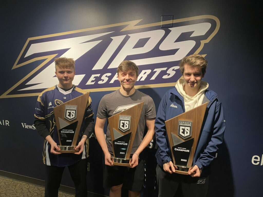 <em>From left to right (.tristn, pattty, bullzeye) holding three of the four Akron ESC Championship Trophies (Image via ZipsEsports on X)</em>